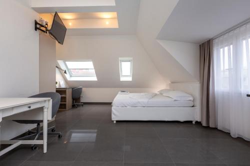 a bedroom with a bed and a desk and window at Hotel Kernhof Self Check-In in Zurich