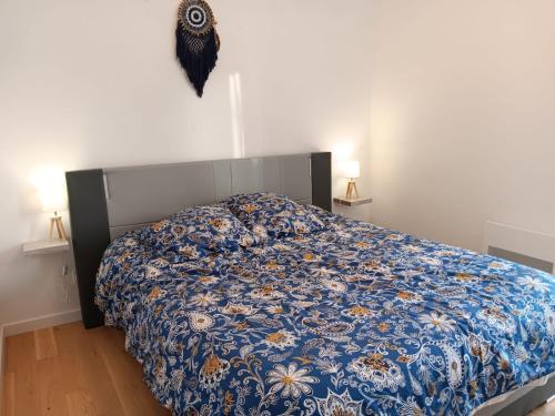 a bedroom with a bed with a blue floral comforter at Maison individuelle 6 personnes in Coux