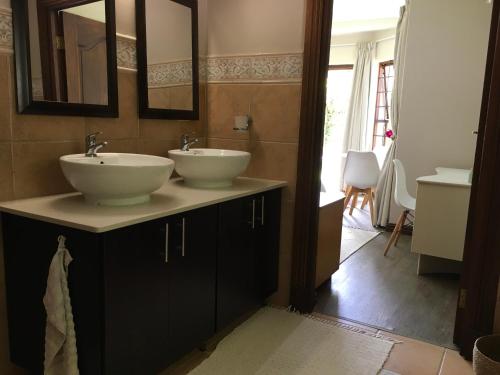 a bathroom with two sinks and mirrors on a counter at Plovers Rest in George
