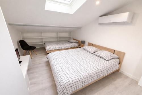 a bedroom with two beds and a chair in it at Duplex 2 chambres Meximieux centre ville in Meximieux