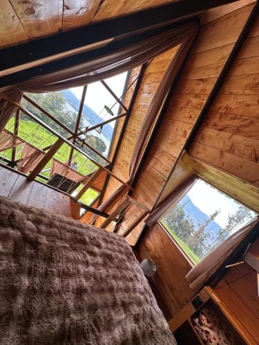 a bedroom in a tree house with windows at Chalet - Laguna de la Cocha in Pasto