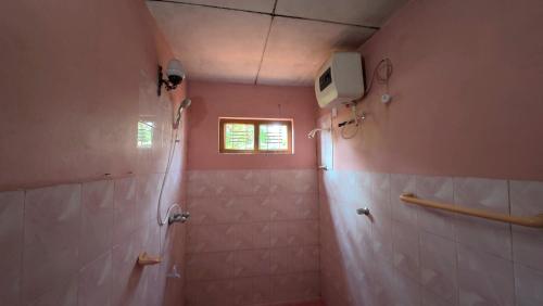 a pink bathroom with a shower and a window at Diws Holiday Bungalow in Anuradhapura