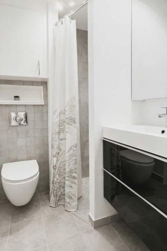 a white bathroom with a toilet and a sink at Cozy Oasis perfect for couples & solo travelers in Viborg