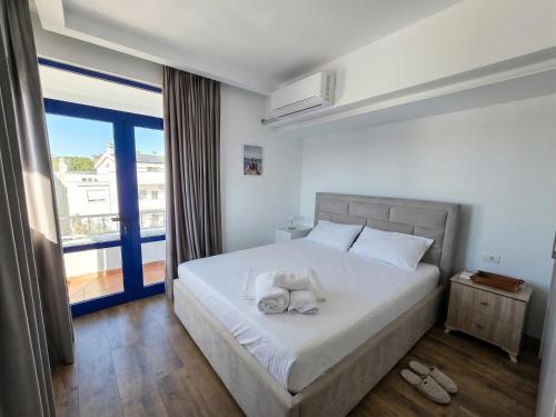 a bedroom with a bed with white sheets and a window at Hotel BlueBalcony in Golem