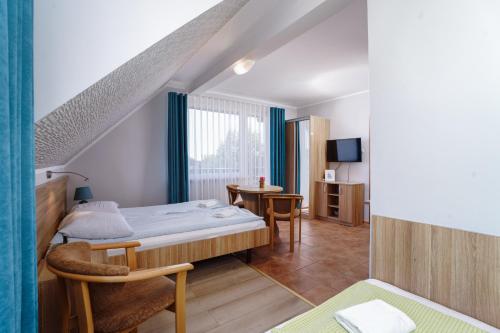 a hotel room with a bed and a table at Willa Karawela in Łeba