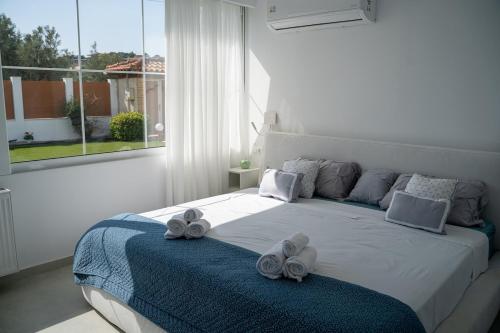 a white bedroom with a bed with towels on it at Villa Oneiron in Anavyssos