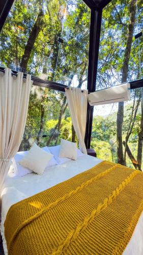 a bedroom with a bed and a window with trees at Cabanas do Valle in Itaara