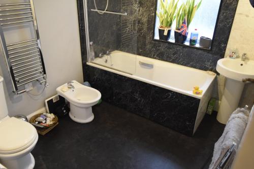 a bathroom with a toilet and a tub and a sink at Crystal Palace B&B in London