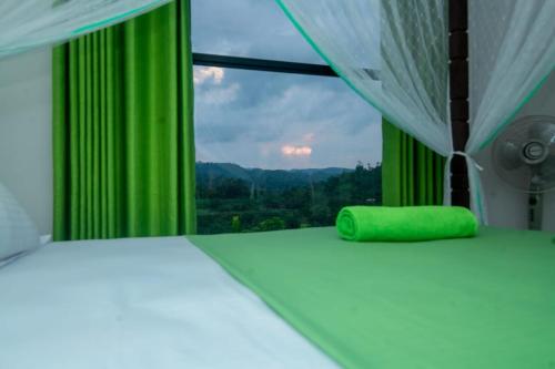 a bedroom with a bed and a window with green curtains at Rainforest Hide View in Deniyaya