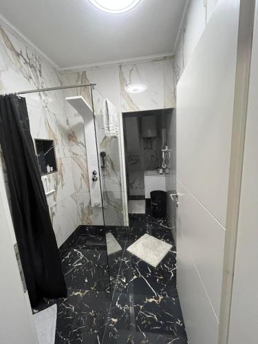a bathroom with a shower and a black marble floor at Guest House Eden in Bihać