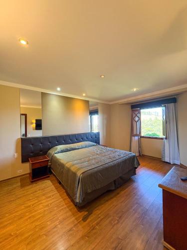 a bedroom with a large bed and a couch at Hotel Home Green Home in Campos do Jordão