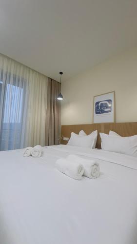 a bedroom with a large white bed with towels on it at Parkside Dighomi in Tbilisi City