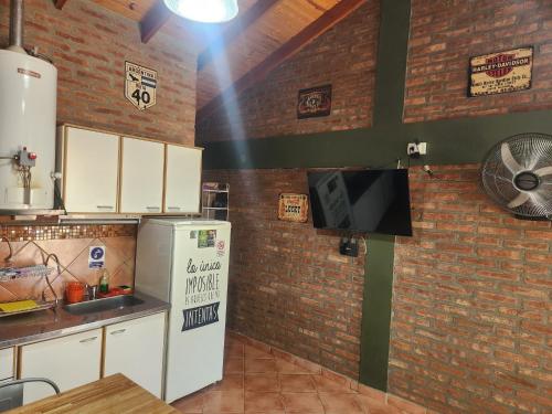 a kitchen with a refrigerator and a brick wall at Los Lúpulos Departamentos Privados in El Bolsón
