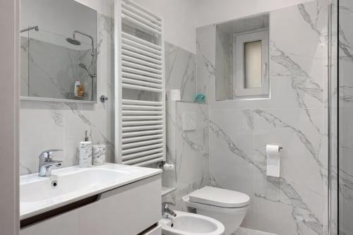 a white bathroom with a sink and a toilet at Trilocale spazioso a 6 minuti dal centro in Trieste