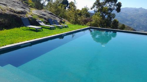 a swimming pool with chairs and mountains in the background at Quinta da Riba Má in Santa Leocádia