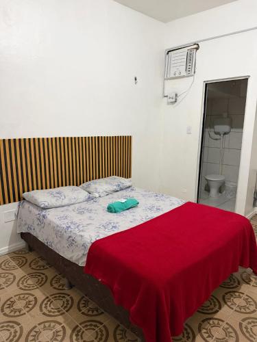 a bedroom with a bed with a red blanket on it at Quarto no centro 207 in Manaus