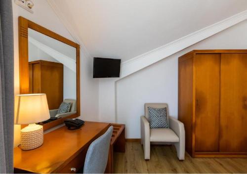 a room with a desk and a mirror and a chair at Hotel Arcanjo in Lagoa