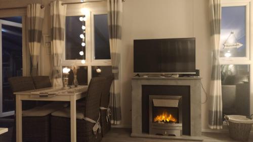 a living room with a fireplace and a television at Luxus Chalet im schönen Recratiepark De Veerstal in Rheden