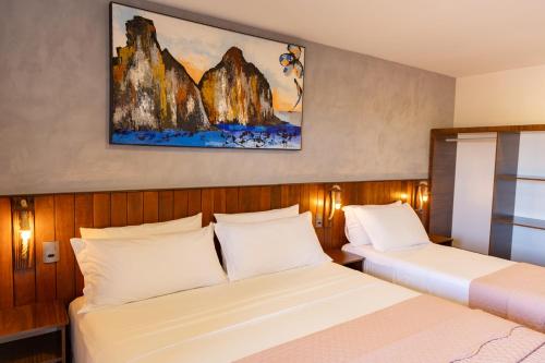 a bedroom with two beds and a painting on the wall at Pousada do Nica in Fernando de Noronha