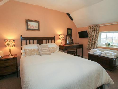 a bedroom with a large white bed and a window at Cariad Cottage in Ludlow