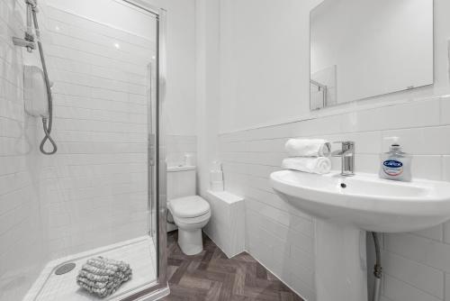 a white bathroom with a sink and a toilet at 1-Bed Duplex with Sofa Bed in Airdrie Lanarkshire - Long Stays - Free Parking in Airdrie