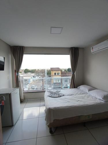 ein Schlafzimmer mit einem Bett und einem großen Fenster in der Unterkunft Hotel Milla in Teixeira de Freitas