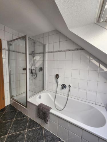 a white bathroom with a shower and a tub at Ferienwohnung Fröse in Altenbeken