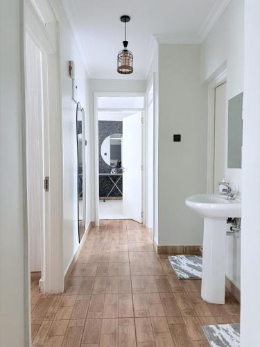 a hallway with a bathroom with a sink and a mirror at Modern 3BR Apt with Pool within UN-Approved Zone, Kiambu Rd in Nairobi