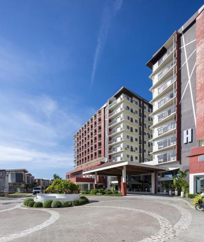 a large building in front of a parking lot at Cara Studio Mactan Cebu Cozy with Garden View at Primeworld District Tower H 103 in Lapu Lapu City