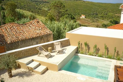 a patio with two chairs and a swimming pool at Viladraga - Casa da Adraga in Colares