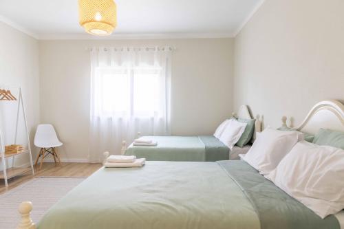 a white bedroom with two beds and a window at Olive House in Fátima