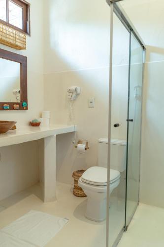 a bathroom with a toilet and a glass shower at Rio Da Barra Villa Hotel in Trancoso