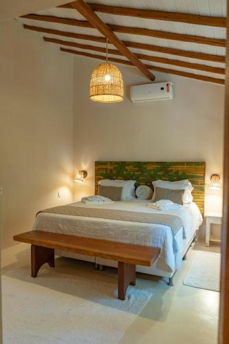 a bedroom with a large bed with a wooden headboard at Rio Da Barra Villa Hotel in Trancoso