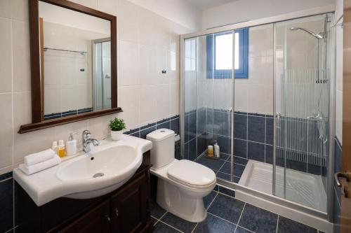 a bathroom with a toilet and a sink and a shower at Livia - Vikles Villas in Pomos