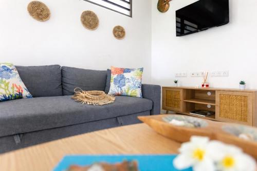 a living room with a couch and a tv at Fare Re'are'a - Charmant bungalow côté mer proche de la plage de Temae in Moorea