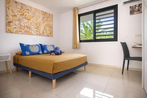 a bedroom with a bed with a window and a chair at Fare Re'are'a - Charmant bungalow côté mer proche de la plage de Temae in Moorea