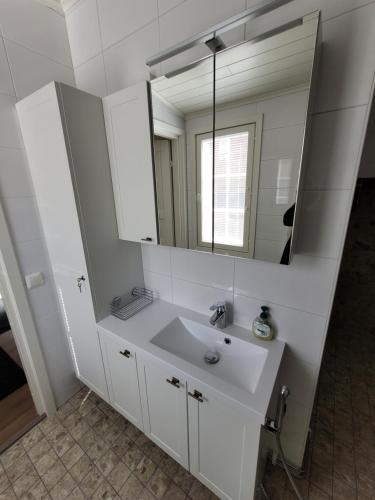 a white bathroom with a sink and a mirror at Majoitus Merihelmi in Kristinestad