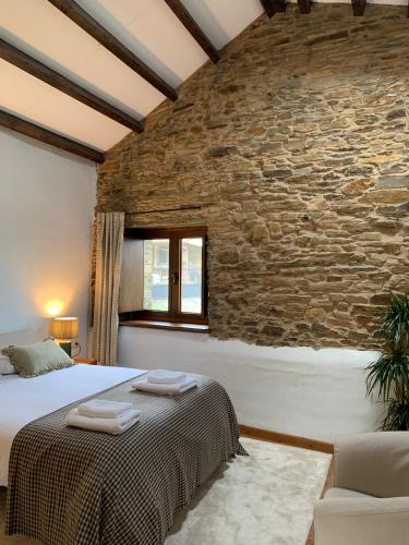 a bedroom with a large bed and a stone wall at Casas do Campo in Monfero