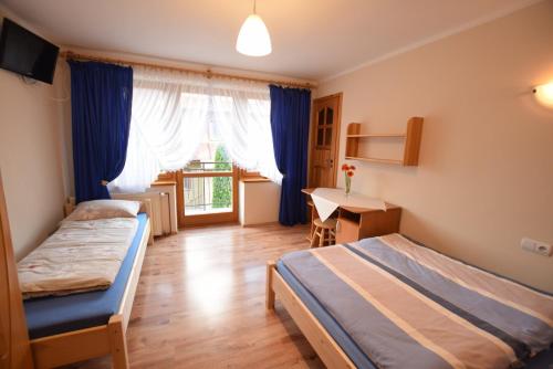 a bedroom with two beds and a desk and a window at Pokoje Gościnne Brynkus in Białka Tatrzańska