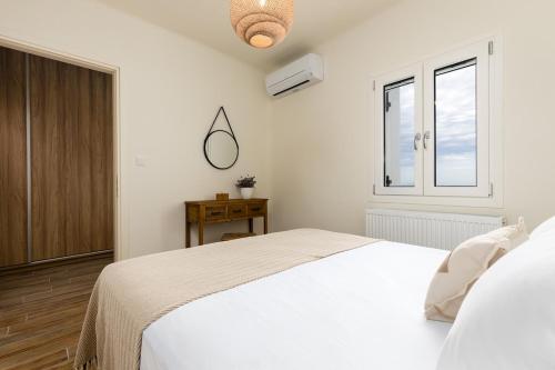 a white bedroom with a bed and a window at Sarris Village Luxury 2 in Sarakíniko