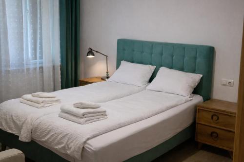 a bed with a blue headboard and towels on it at Casa Centrale with Free Parking in Plovdiv