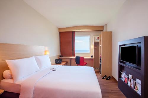 a hotel room with a bed and a flat screen tv at Ibis Manado City Center Boulevard in Manado
