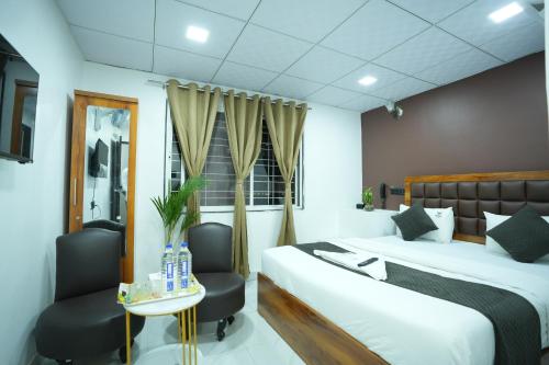 a hotel room with a bed and two chairs at Elysia By THL-Near Westend Mall Aundh in Pune
