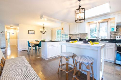 a kitchen with white cabinets and a island with bar stools at Less than 5 Miles to Rock Harbor in Orleans