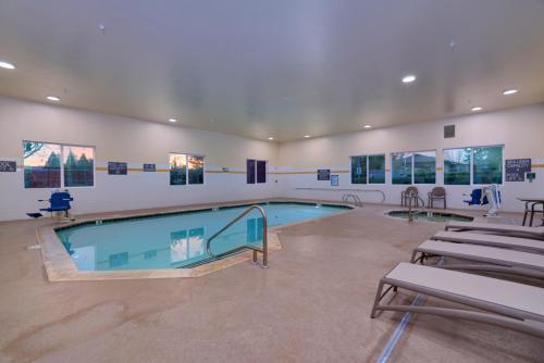 a swimming pool in a room with tables and chairs at Comfort Suites Springfield-Eugene in Springfield