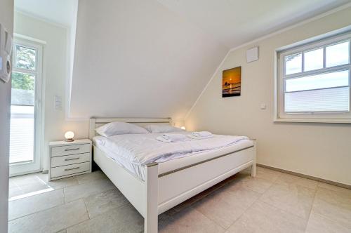 a white bedroom with a bed and a window at Strandvej in Prerow