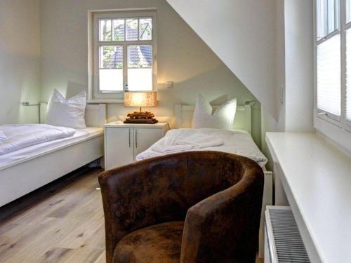 a bedroom with a chair and a bed and a window at Strandhus in Prerow