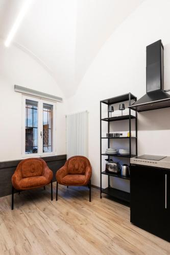 two orange chairs in a room with a kitchen at Ca' Lumaga -Charming Holiday Studio in Chiavenna