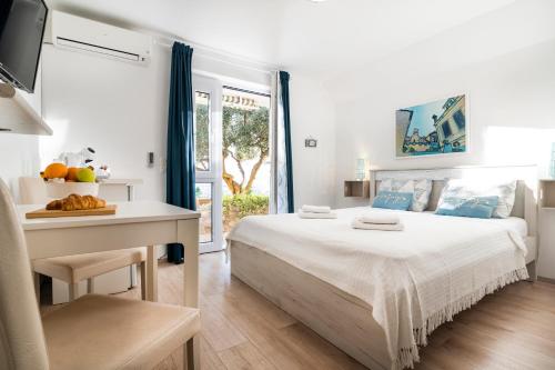 a white bedroom with a large bed and a table at Guest House Kovacevic in Hvar