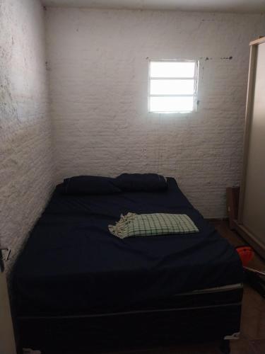 a bedroom with a bed with a blue comforter and a window at Sitio de Antonio à 18km do parque do povo in Campina Grande